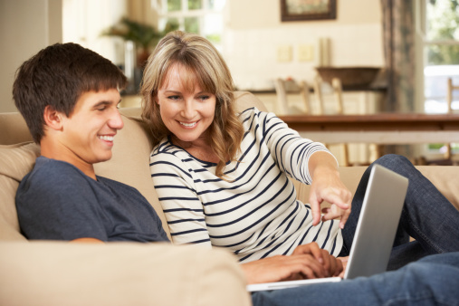 Mother With Teenage Son Sitting On Sofa At Home